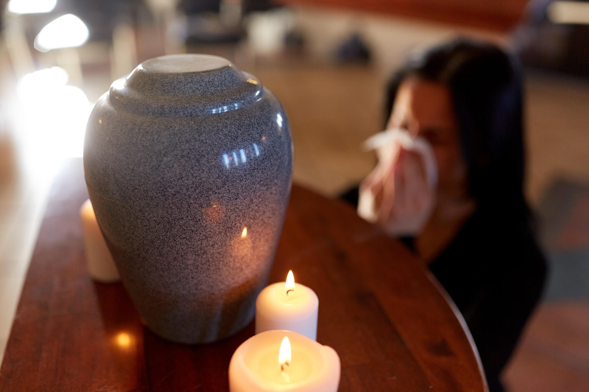 Urn and Candles on table with person mourning